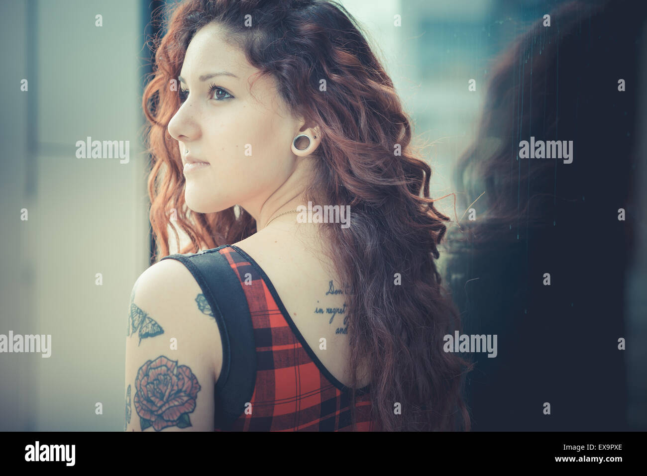 Belle jeune femme hippie avec les cheveux bouclés rouge dans la ville Banque D'Images