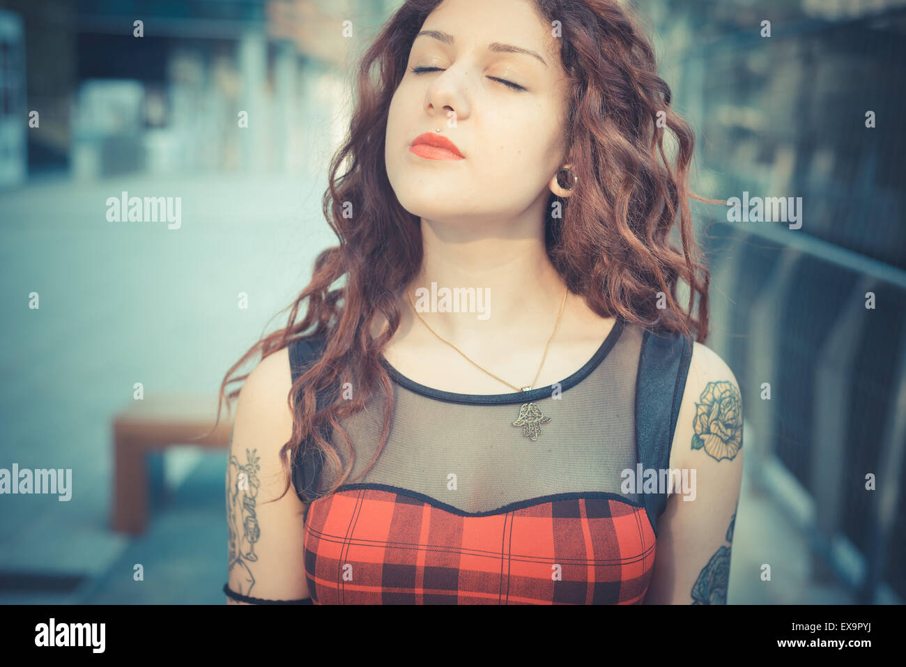 Belle jeune femme hippie avec les cheveux bouclés rouge dans la ville Banque D'Images