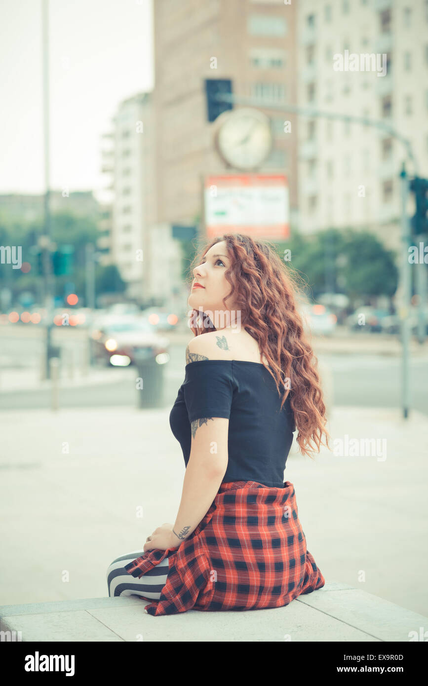 Belle jeune femme hippie avec les cheveux bouclés rouge dans la ville Banque D'Images
