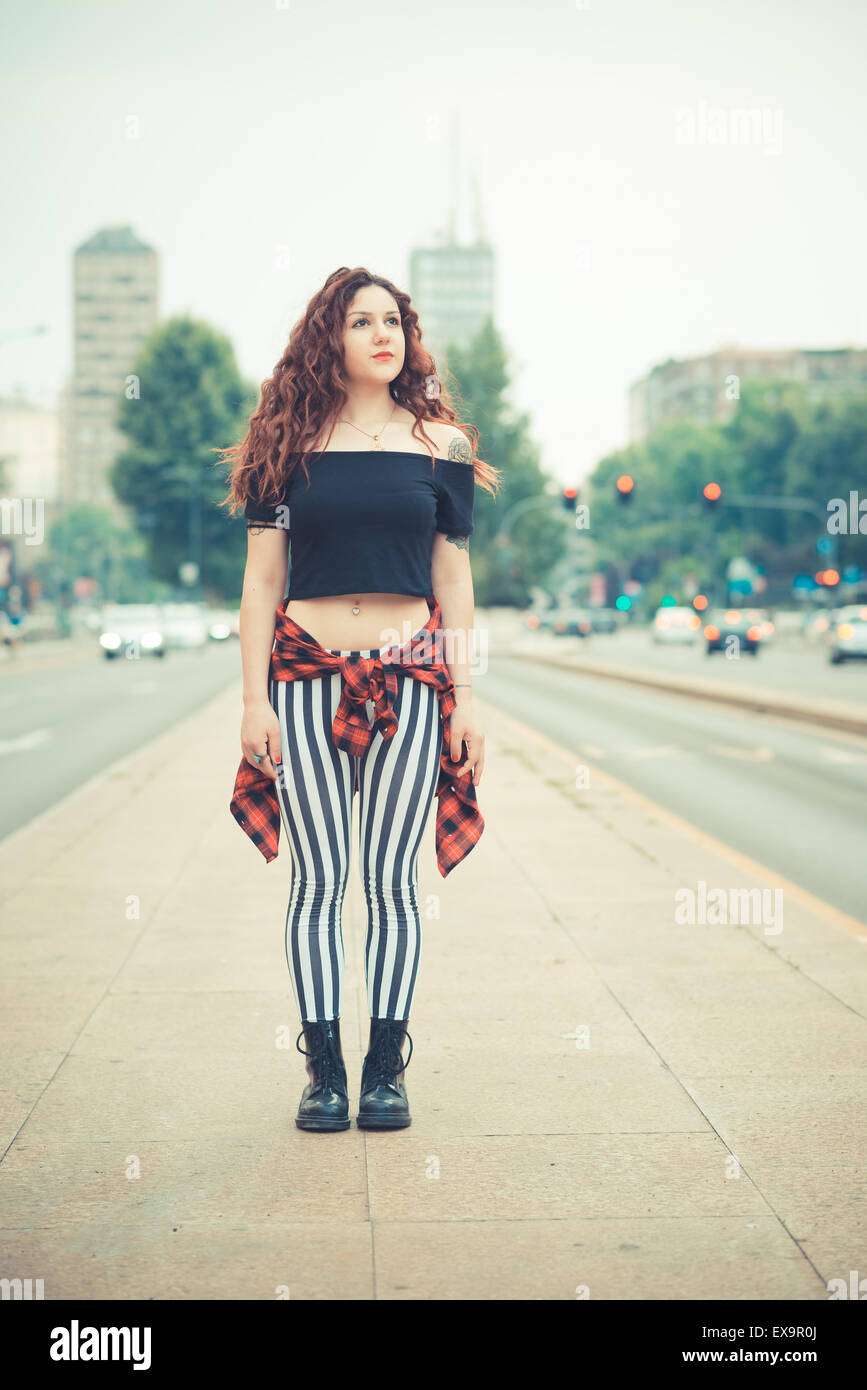 Belle jeune femme hippie avec les cheveux bouclés rouge dans la ville Banque D'Images