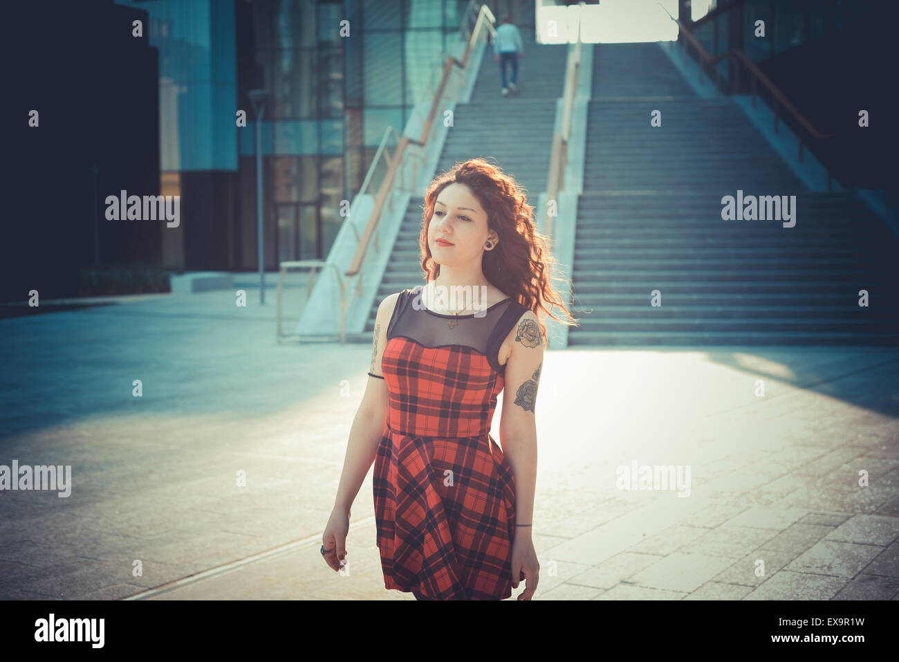 Belle jeune femme hippie avec les cheveux bouclés rouge dans la ville Banque D'Images