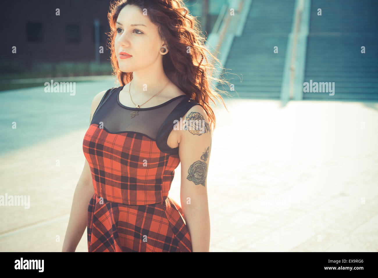 Belle jeune femme hippie avec les cheveux bouclés rouge dans la ville Banque D'Images