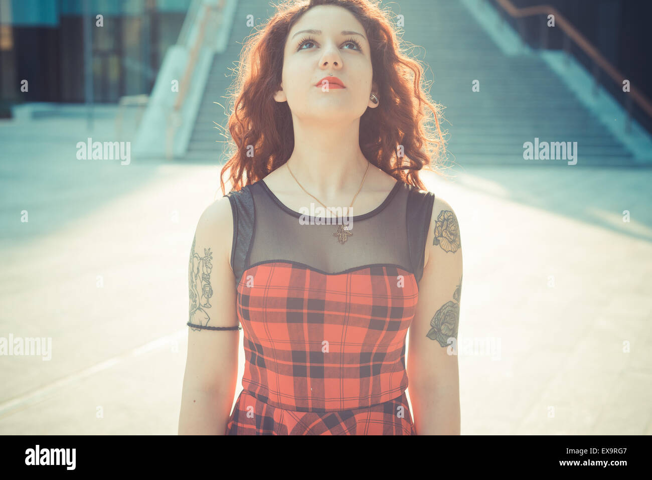 Belle jeune femme hippie avec les cheveux bouclés rouge dans la ville Banque D'Images