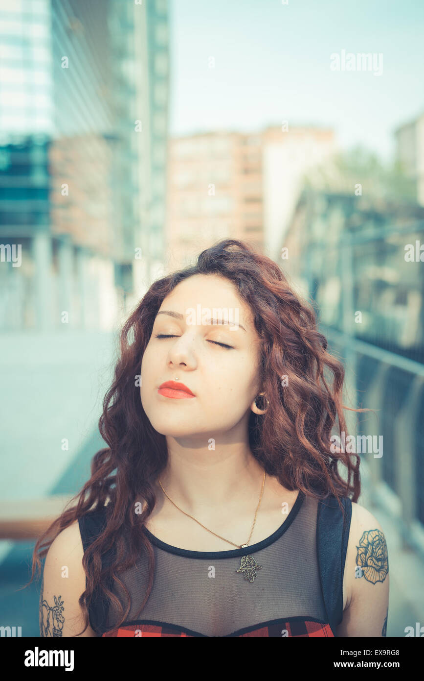 Belle jeune femme hippie avec les cheveux bouclés rouge dans la ville Banque D'Images