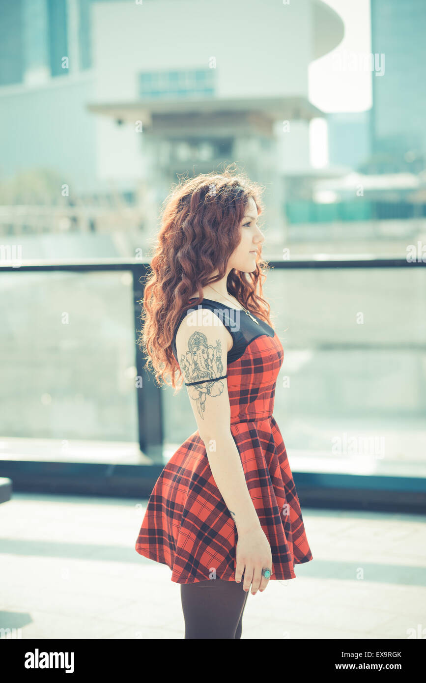 Belle jeune femme hippie avec les cheveux bouclés rouge dans la ville Banque D'Images