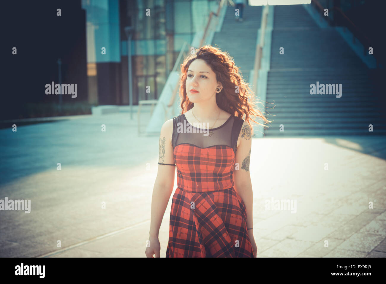 Belle jeune femme hippie avec les cheveux bouclés rouge dans la ville Banque D'Images