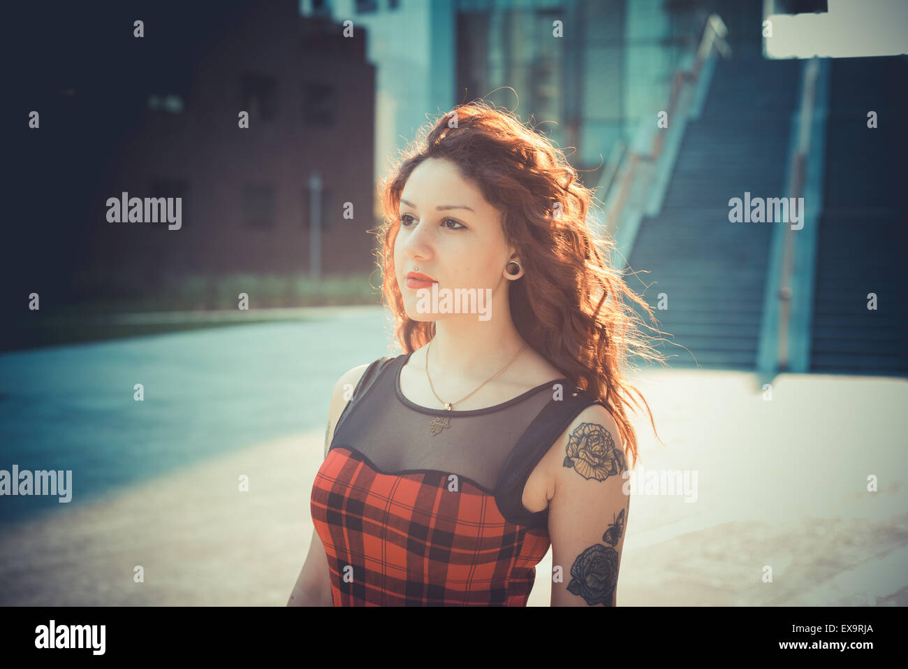 Belle jeune femme hippie avec les cheveux bouclés rouge dans la ville Banque D'Images