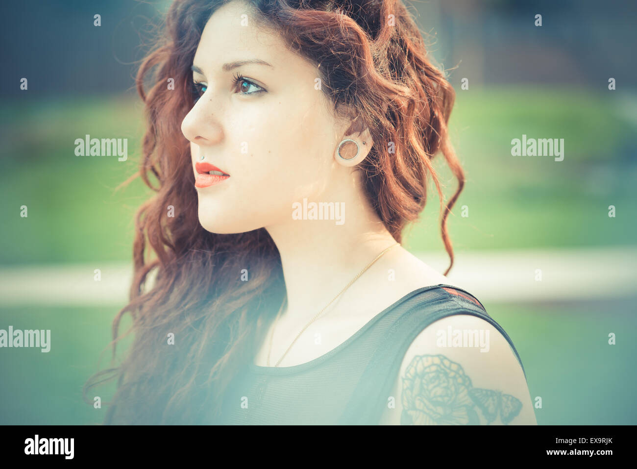 Belle jeune femme hippie avec les cheveux bouclés rouge dans la ville Banque D'Images