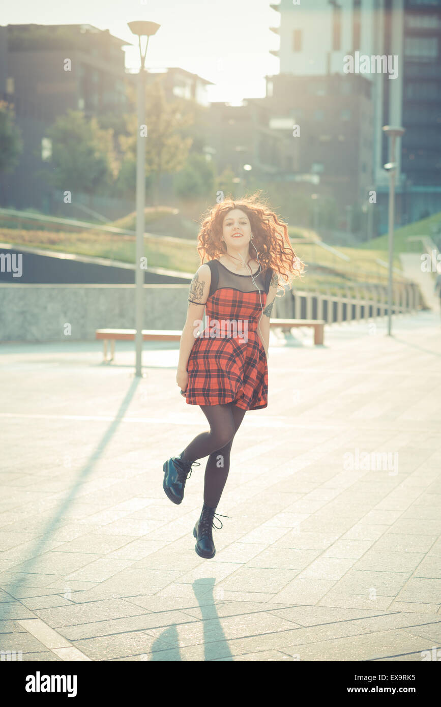 Belle jeune femme hippie avec les cheveux bouclés rouge dans la ville Banque D'Images