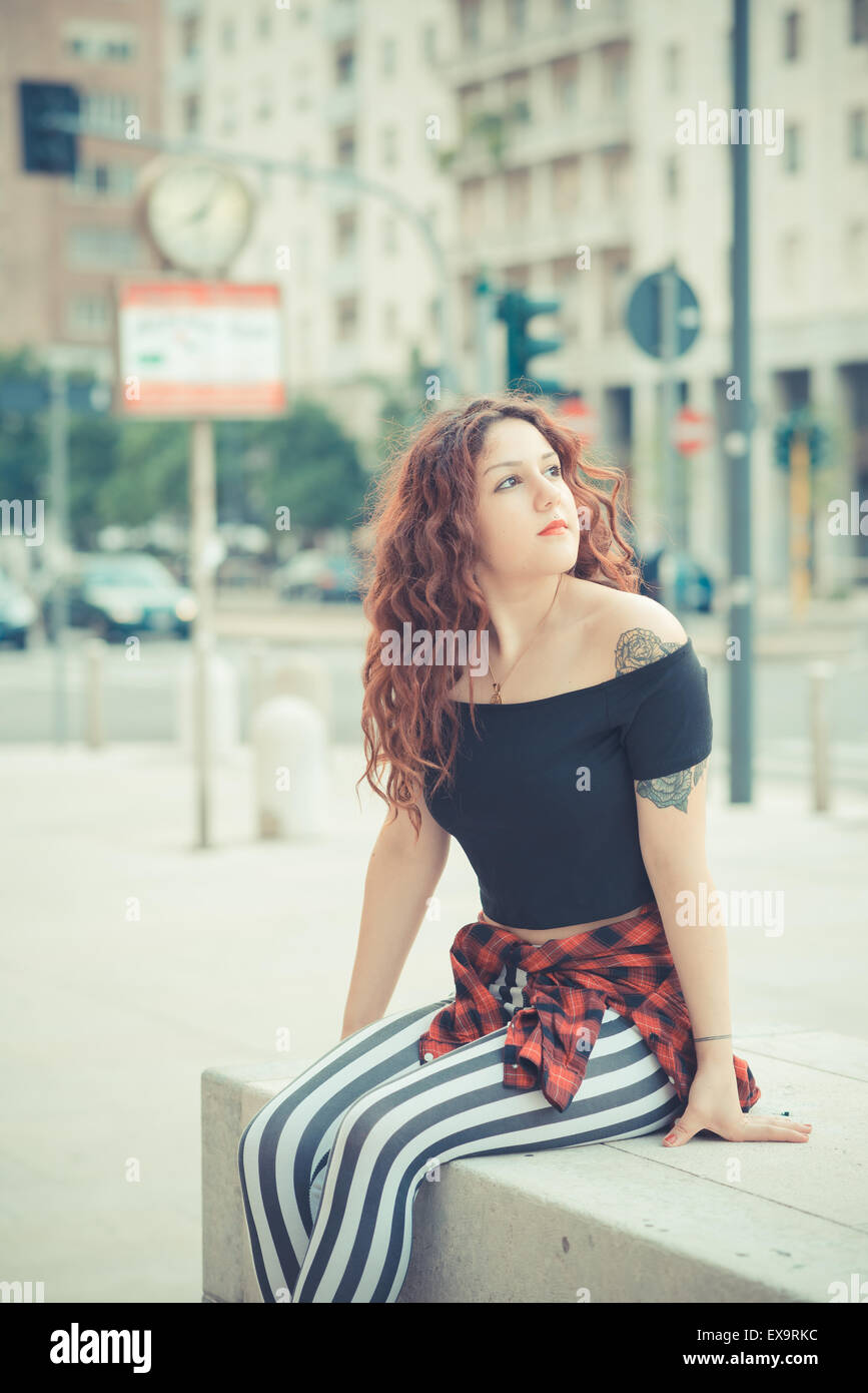 Belle jeune femme hippie avec les cheveux bouclés rouge dans la ville Banque D'Images