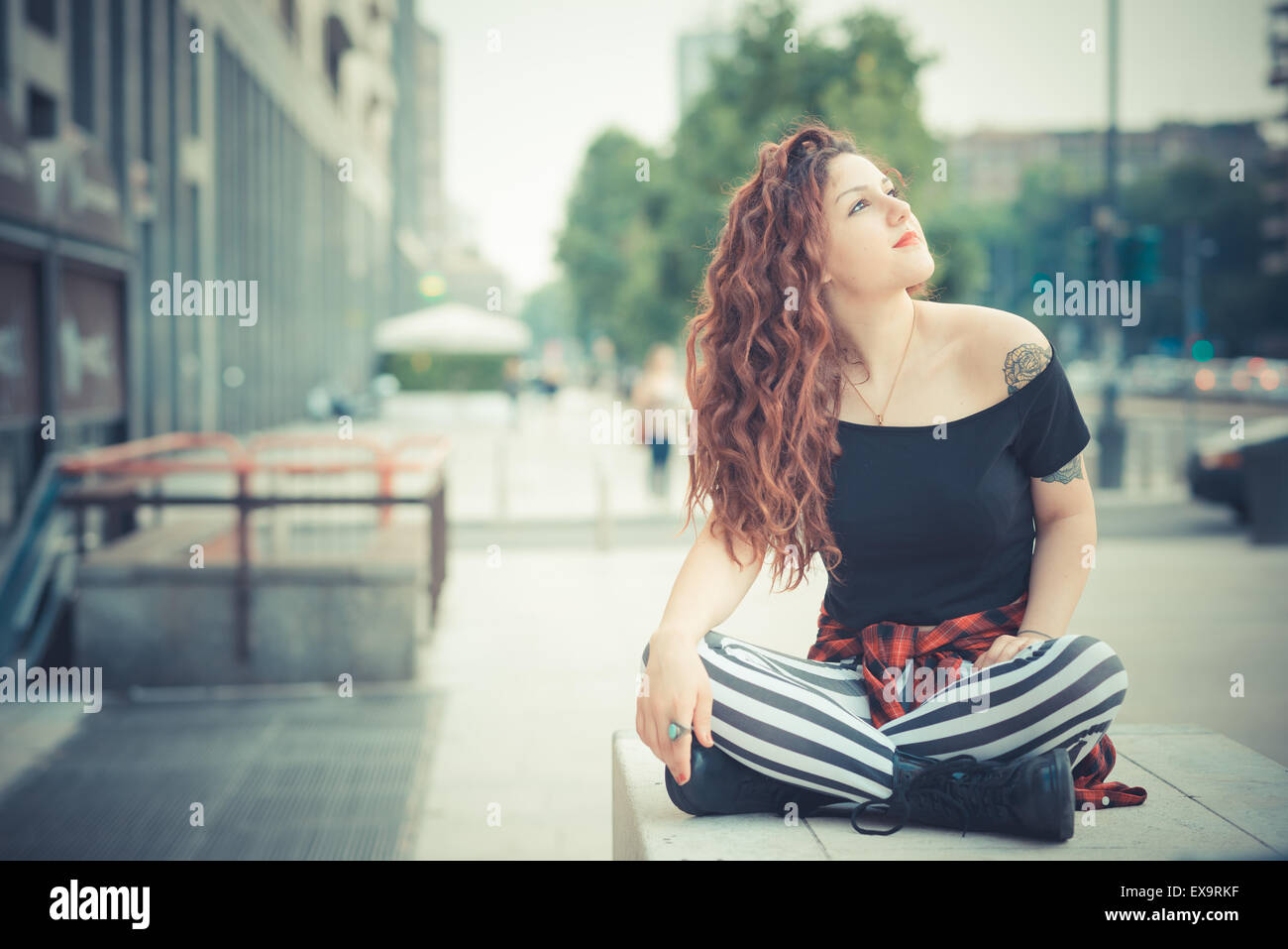 Belle jeune femme hippie avec les cheveux bouclés rouge dans la ville Banque D'Images