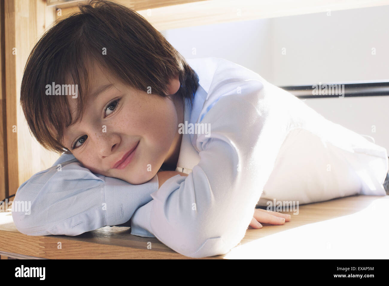 Boy resting head on arms, smiling, portrait Banque D'Images