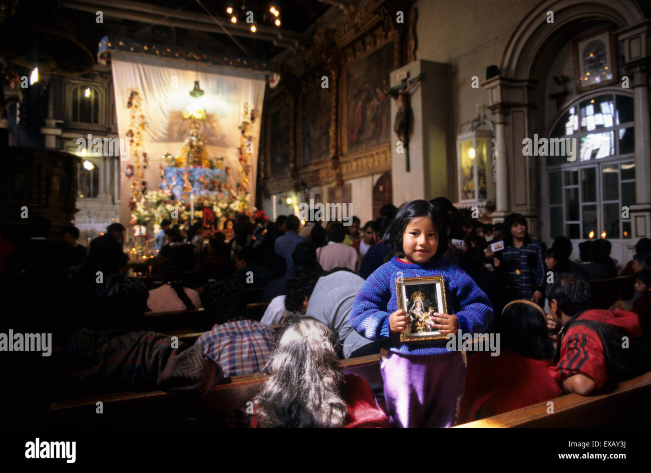 Paucartambo, Pérou. Petite fille tenant une photo de la Vierge de Carmen dans l'église avant la procession. Banque D'Images