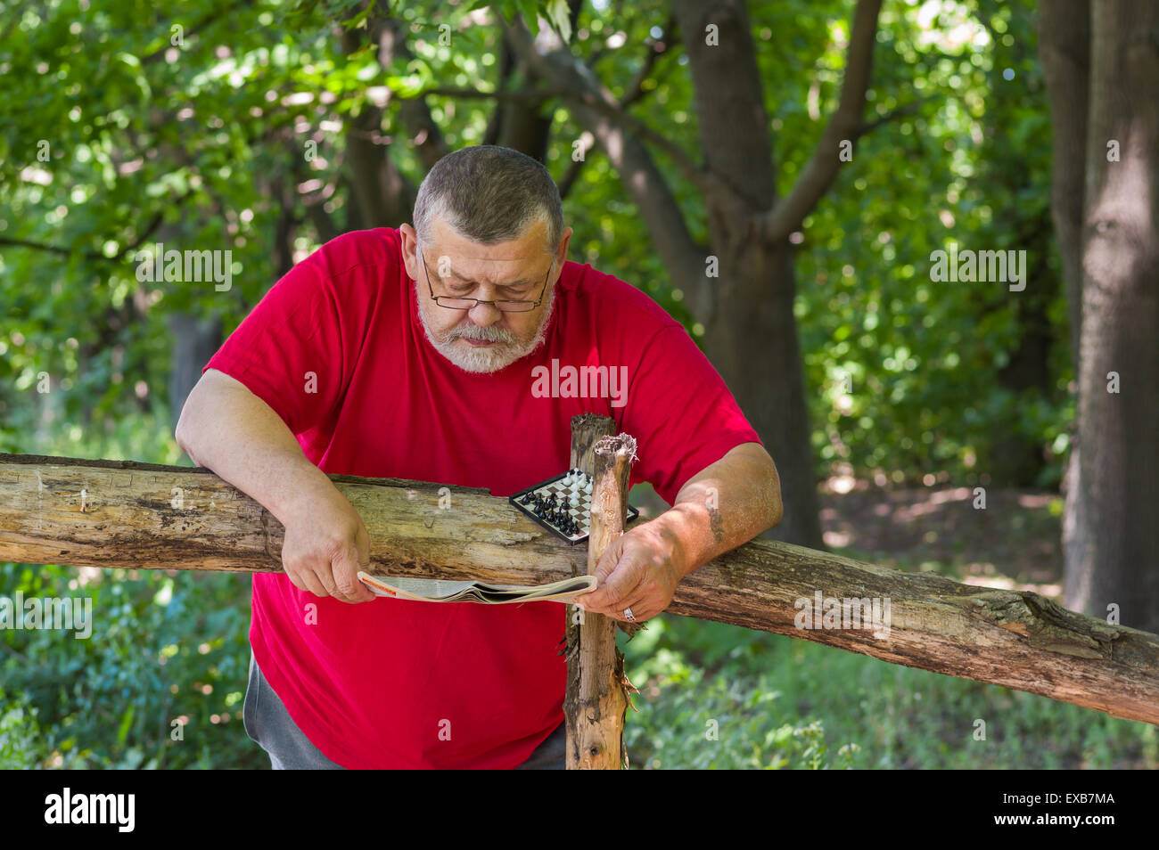 Homme barbu Senior reading newspaper in park Banque D'Images