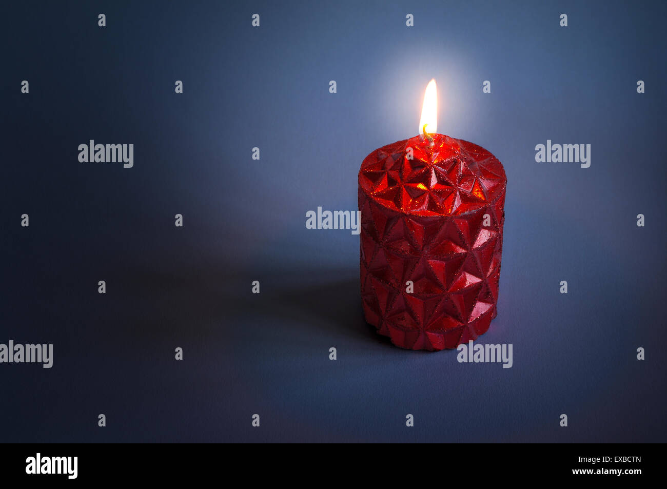 Bougie de Noël rouge allumée et brillant dans l'obscurité. Banque D'Images