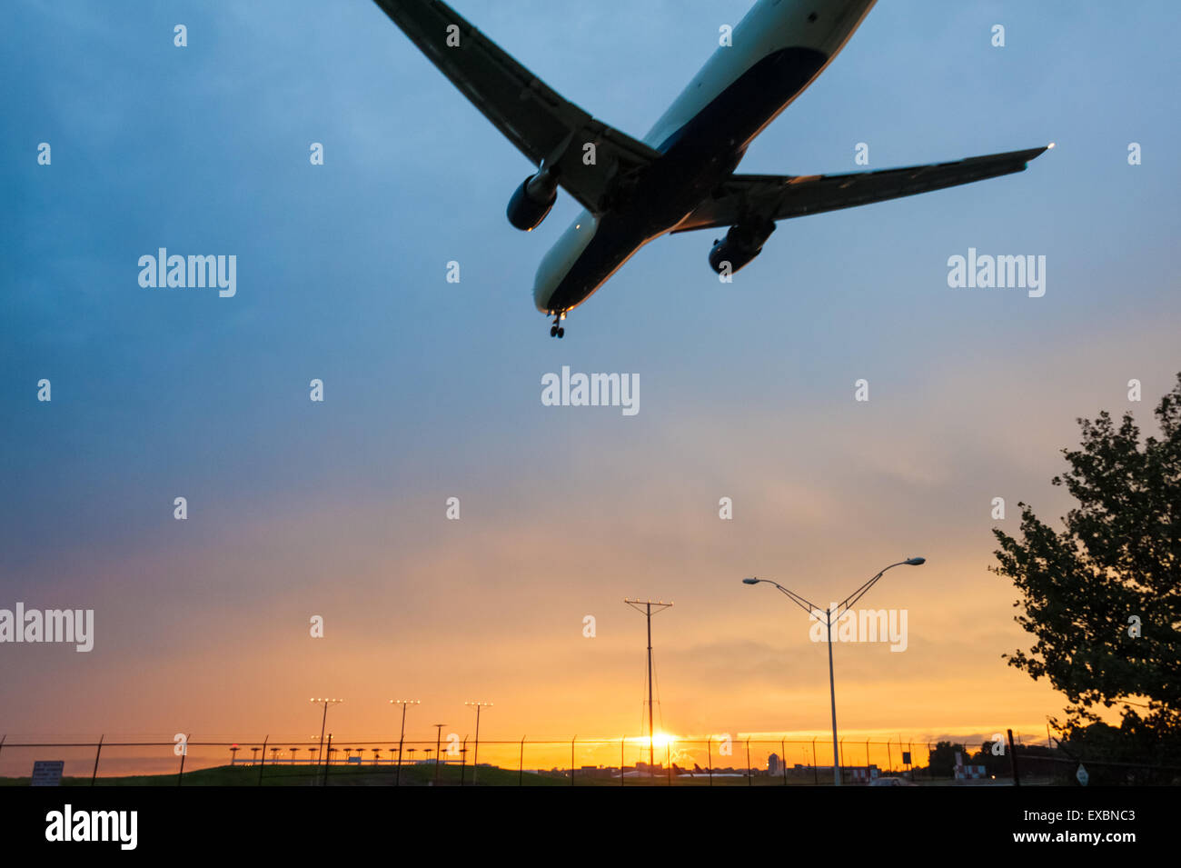 Delta Airlines jet volant à basse altitude à l'approche de la piste de l'Aéroport International d'Atlanta sous un ciel coucher de soleil coloré. (USA) Banque D'Images