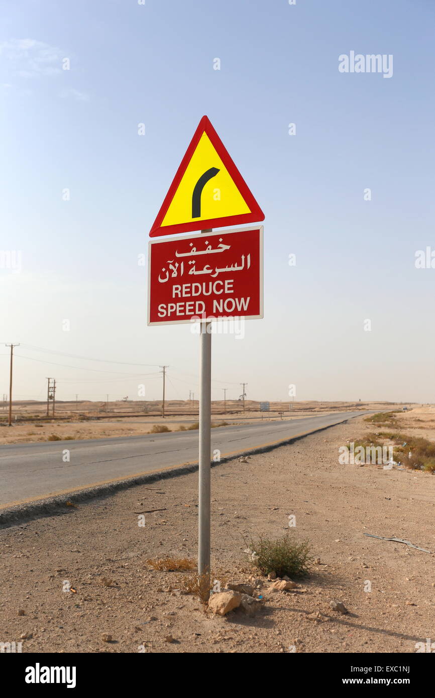 Une signalisation routière en arabe et français raconter les automobilistes à réduire leur vitesse en raison d'un virage de la route, Royaume de Bahreïn Banque D'Images