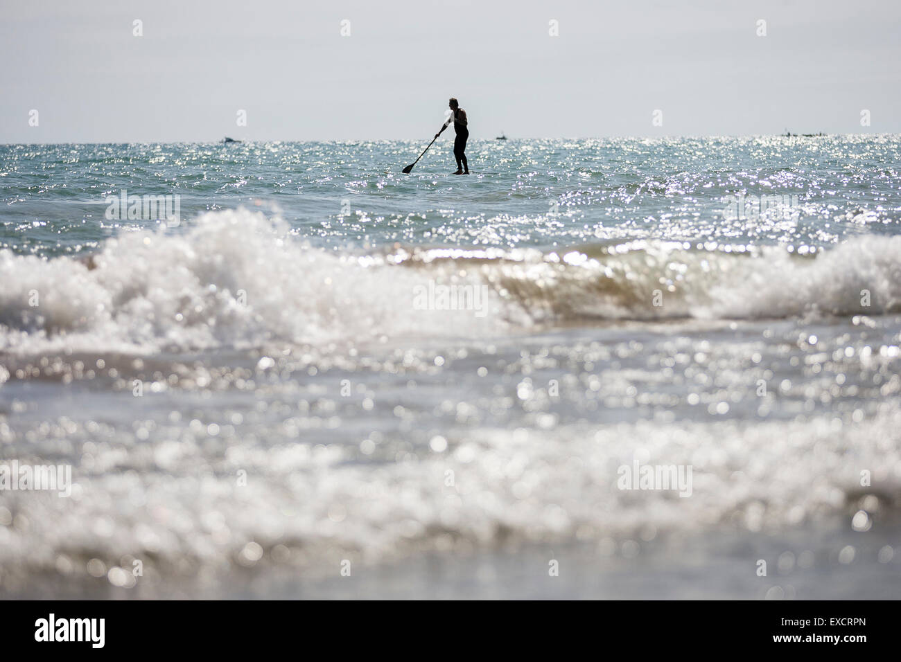 Un homme paddle boards sur une planche de surf sur le lac Michigan à l'été. Banque D'Images