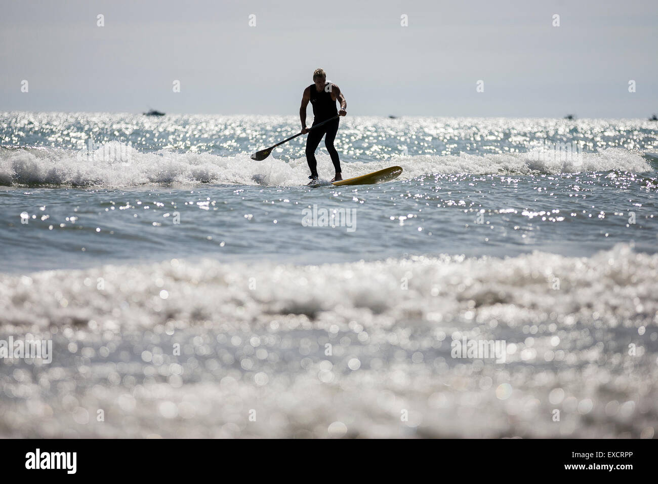 Un homme paddle boards sur une planche de surf sur le lac Michigan à l'été. Banque D'Images