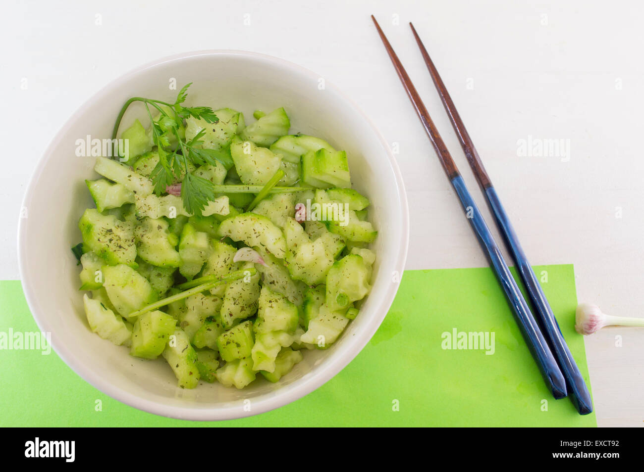 Salade avec des courges et cucamber avec oignon persil à côté de baguettes japonaises sur fond vert servi Banque D'Images