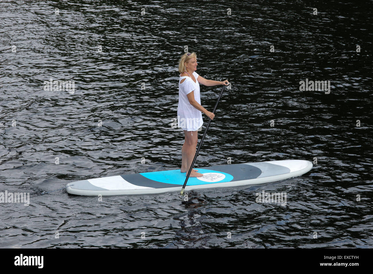 Blonde woman paddling une pagaie sangliers sur le lac Long New York USA US Banque D'Images