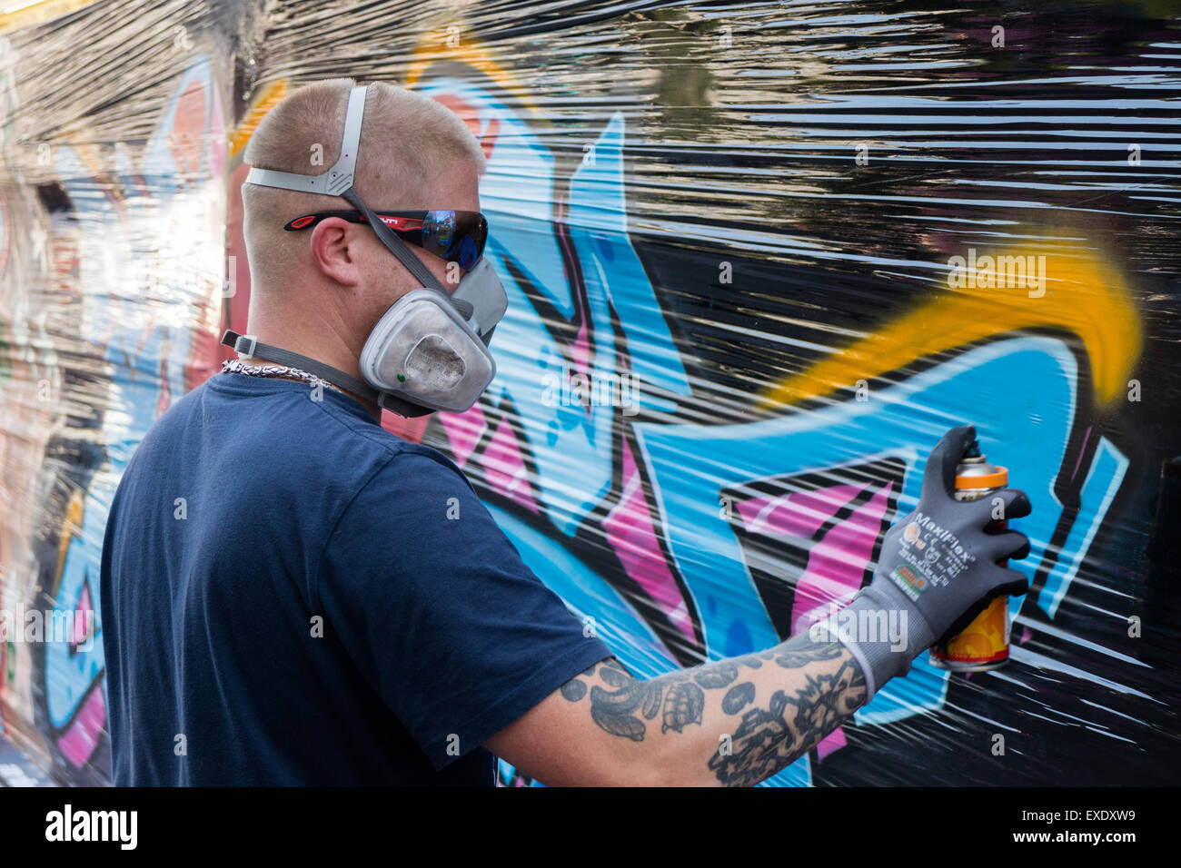 Un graffiti artiste utilise un aérosol de peinture sur un mur à peindre une image Banque D'Images