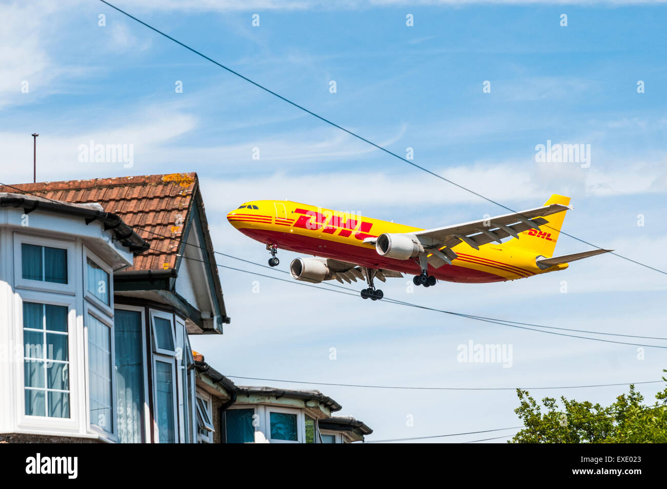 Vue latérale d'un Airbus A300 DHL cargo passant à basse altitude au-dessus des maisons qui entourent l'aéroport London Heathrow Banque D'Images