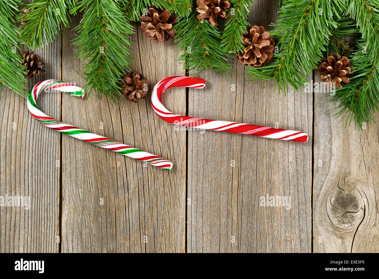 Frontière de Noël avec des branches d'arbre de pin, cônes et des cannes de bonbon sur planches de bois rustique. Banque D'Images