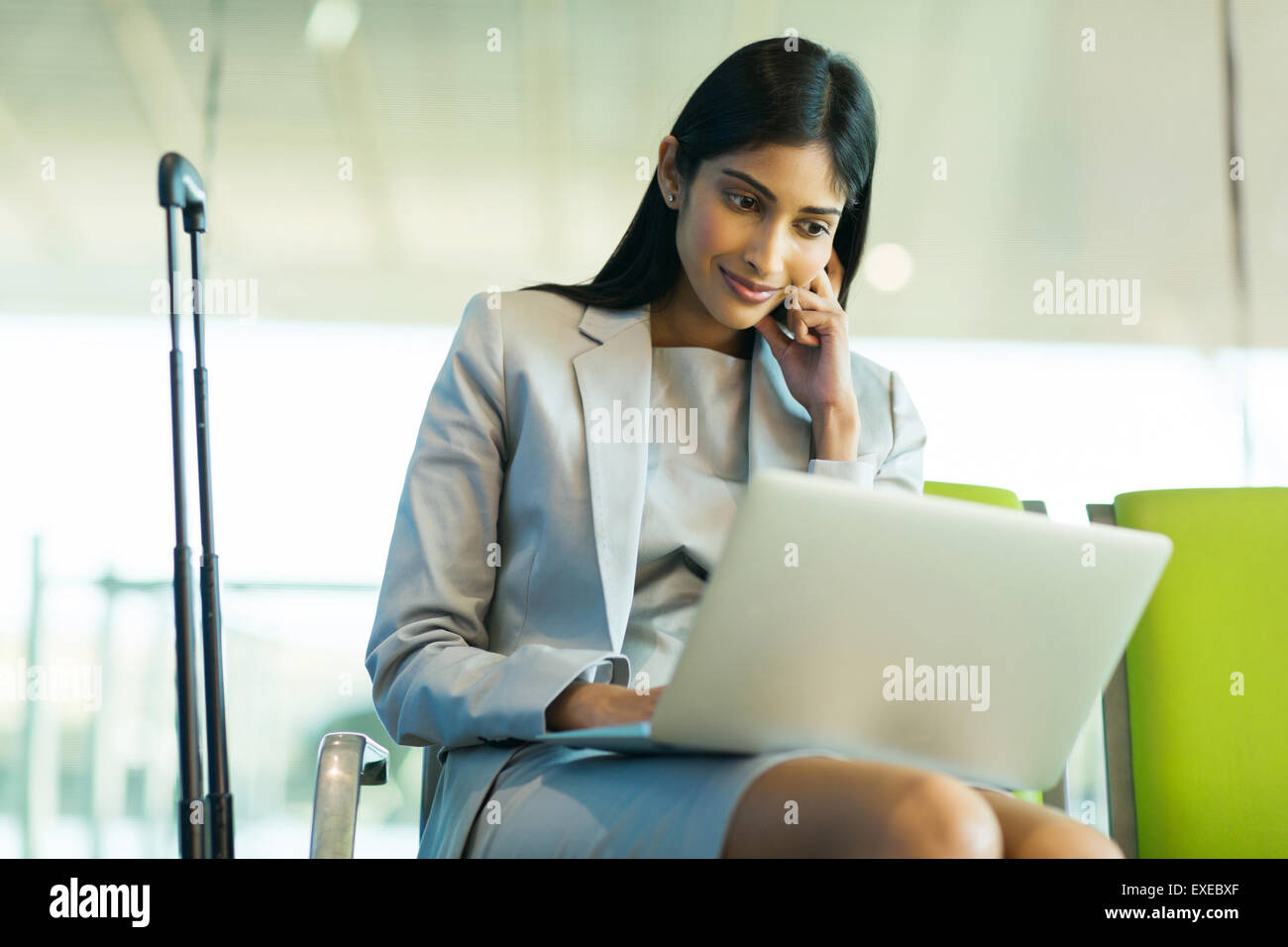 Succès Indian businesswoman using laptop computer at airport Banque D'Images