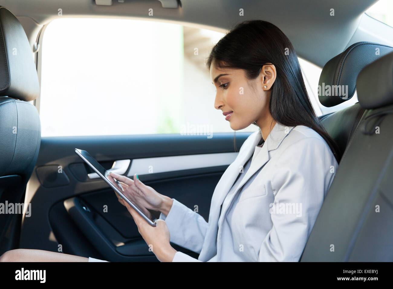 Indian business woman using tablet pc in backseat of car Banque D'Images