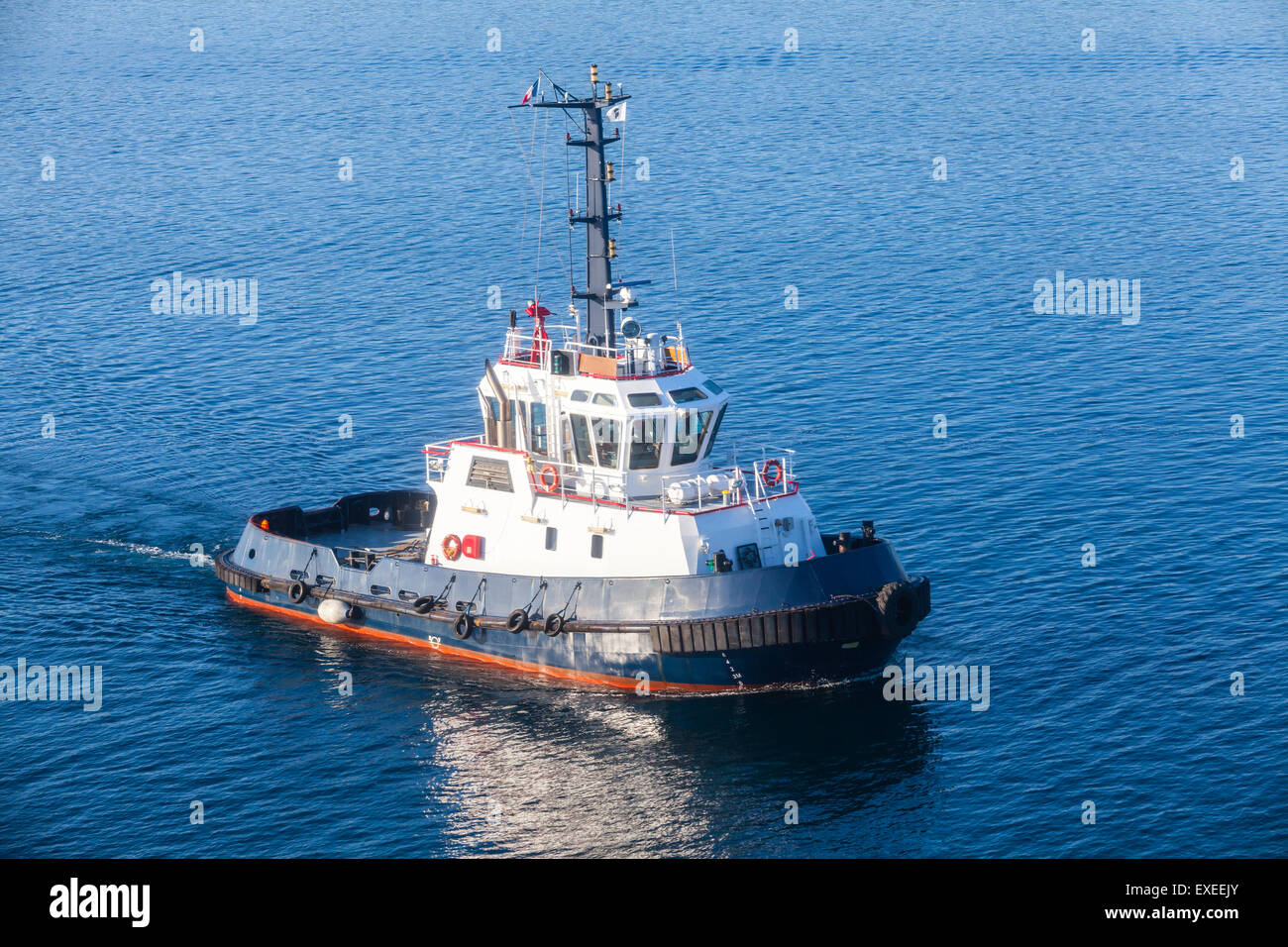 Tug boat avec superstructure blanc et bleu foncé coque en cours sur l'eau de mer Banque D'Images