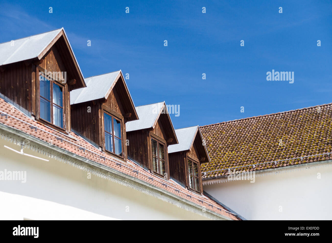 Tuiles du toit et les fenêtres des chambres mansardées contre le ciel bleu Banque D'Images