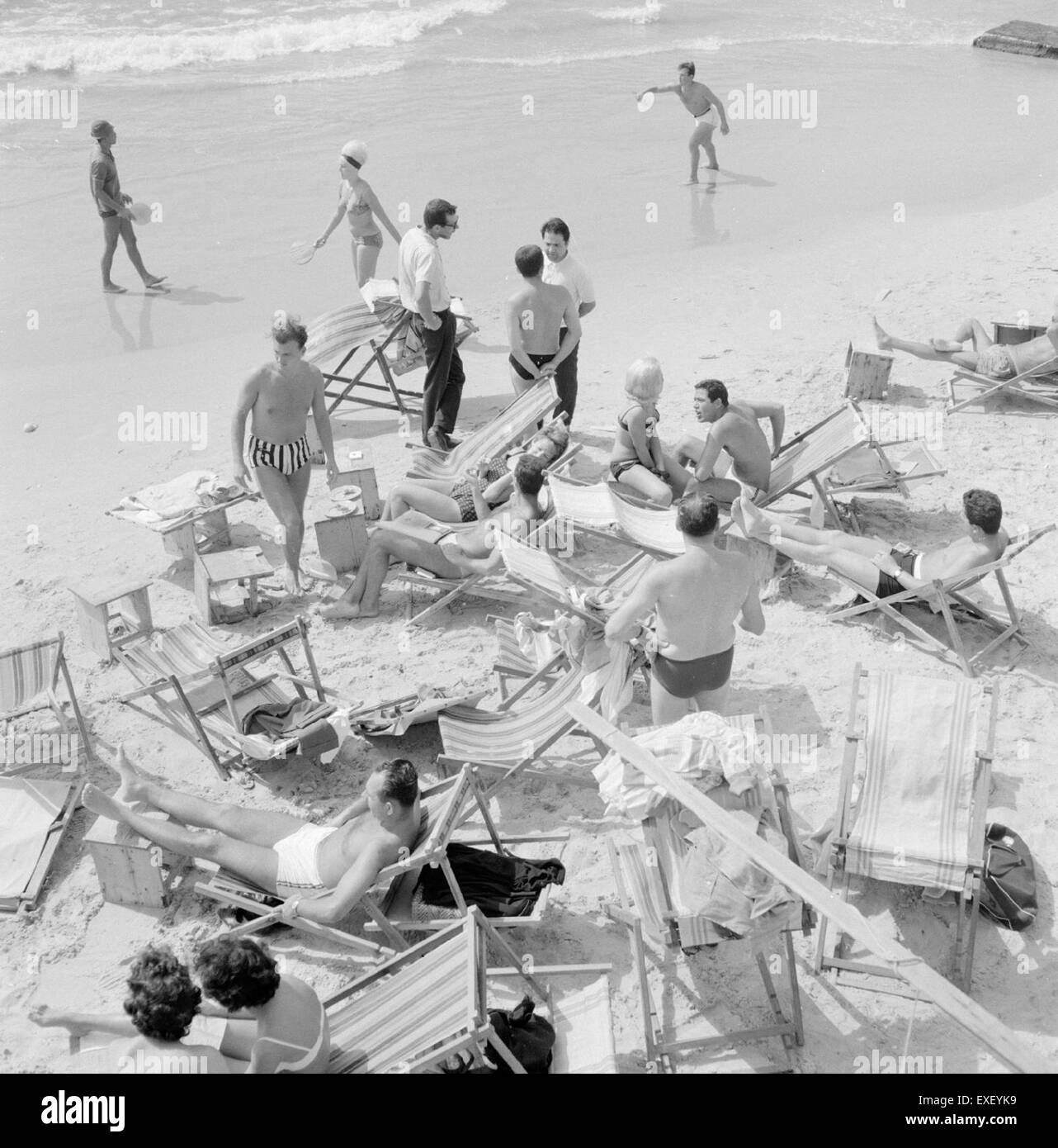 Une photographie de bronzeurs sur la plage de tel Aviv, capturant l'atmosphère animée de la côte méditerranéenne populaire. L'image montre des gens se relaxant sur la rive sablonneuse, profitant du temps chaud. Banque D'Images
