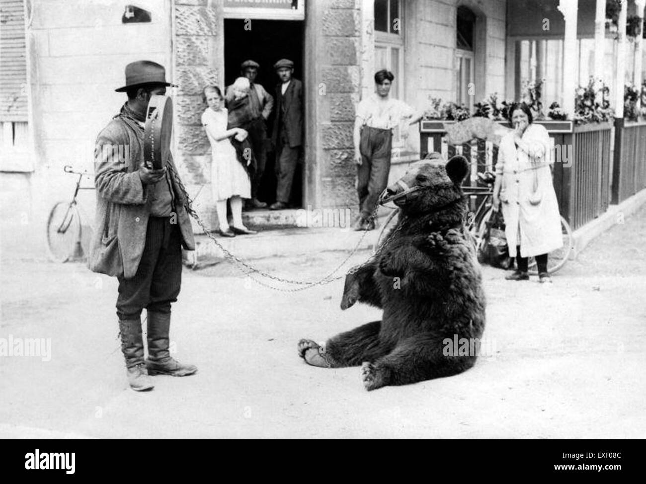 La peinture 'animal Trainer with Performing Bear' représente un entraîneur d'animaux dans un cadre de cirque, mettant en valeur les compétences de l'entraîneur dans la manipulation d'un ours performant. Banque D'Images
