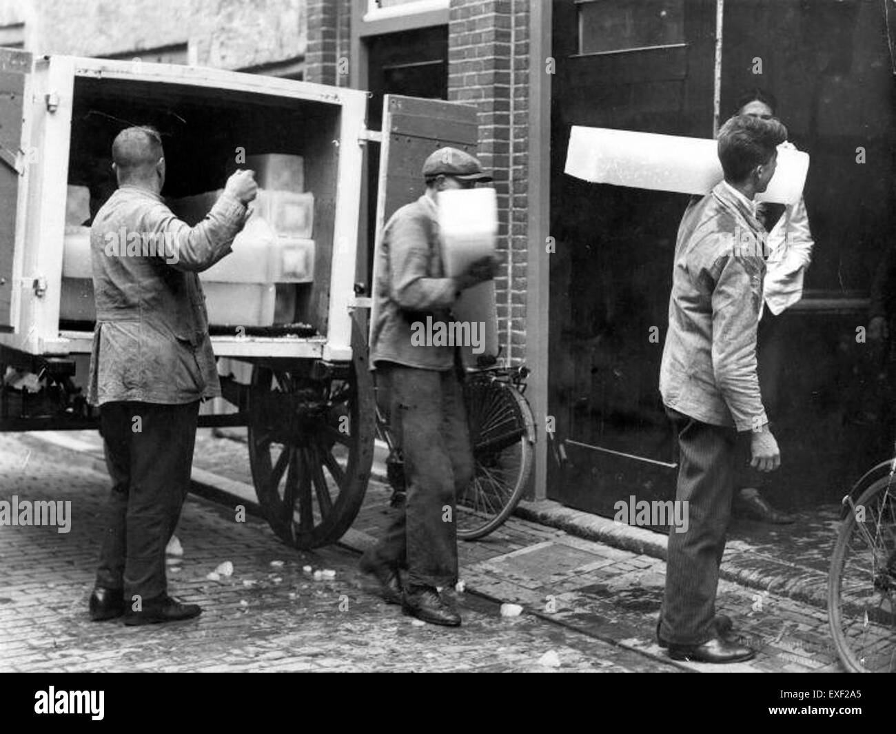 La photographie capture *IJsdragers*, ou hommes livrant de la glace, une pratique courante dans le passé avant la réfrigération moderne. L'image reflète les méthodes historiques de transport de glace, montrant les travailleurs qui chargent et transportent de la glace dans un contexte de livraison en entreposage frigorifique. Banque D'Images