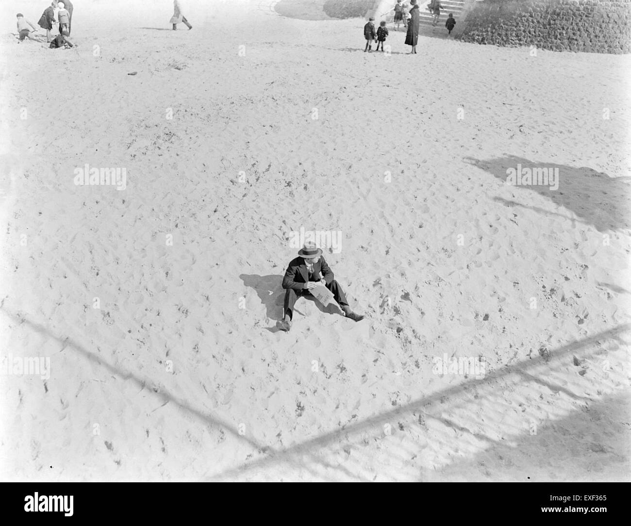 Un homme marchant le long de la plage, avec l'océan et le ciel en arrière-plan, interagissant avec l'environnement naturel. Banque D'Images