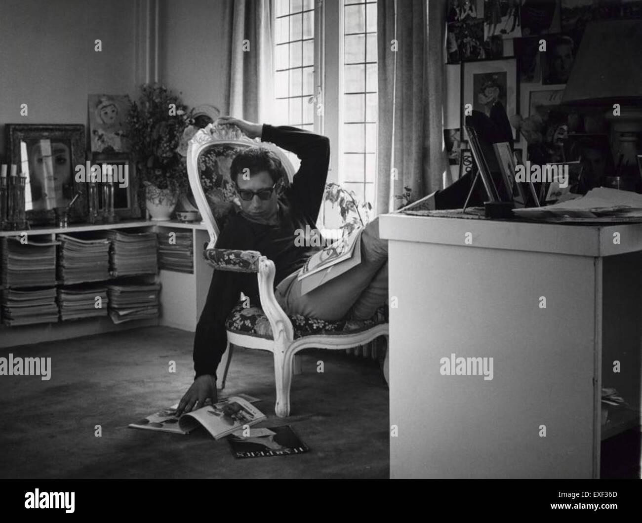 Une image de Max Heymans feuilletant de façon décontractée des magazines de mode, incarnant un moment de détente dans son exploration des tendances de la mode. L'œuvre dépeint un moment de loisir tout en mettant en valeur l'engagement de Heymans avec la culture de la mode. Banque D'Images