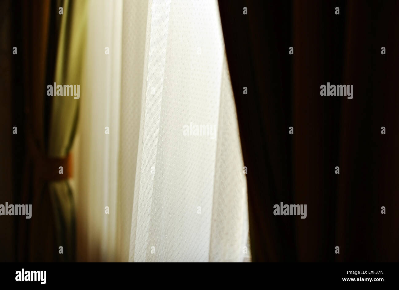 Détail de l'intérieur avec un rideau de velours vert tourné contre la lumière extérieure chaude Banque D'Images