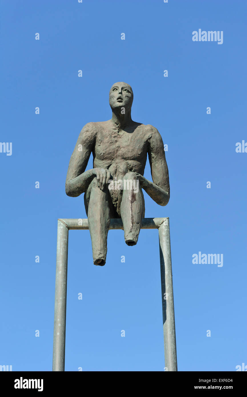 Une sculpture d'un homme sans pieds assis sur une barre de métal dans l'air, Santorini, Grèce. Banque D'Images