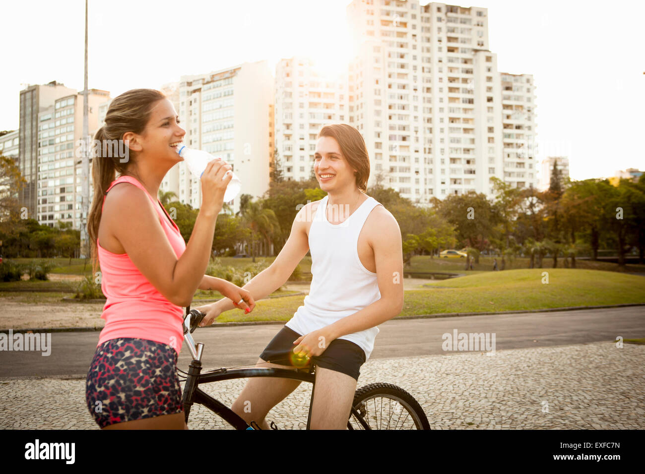 Jeune couple chatting tout en se préparant à cycle dans park Banque D'Images