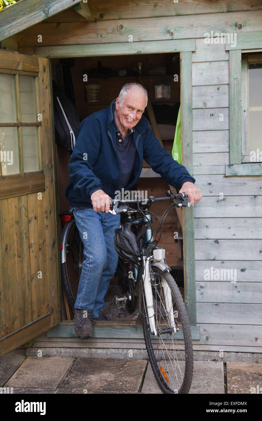 Senior man on bike par shed Banque D'Images