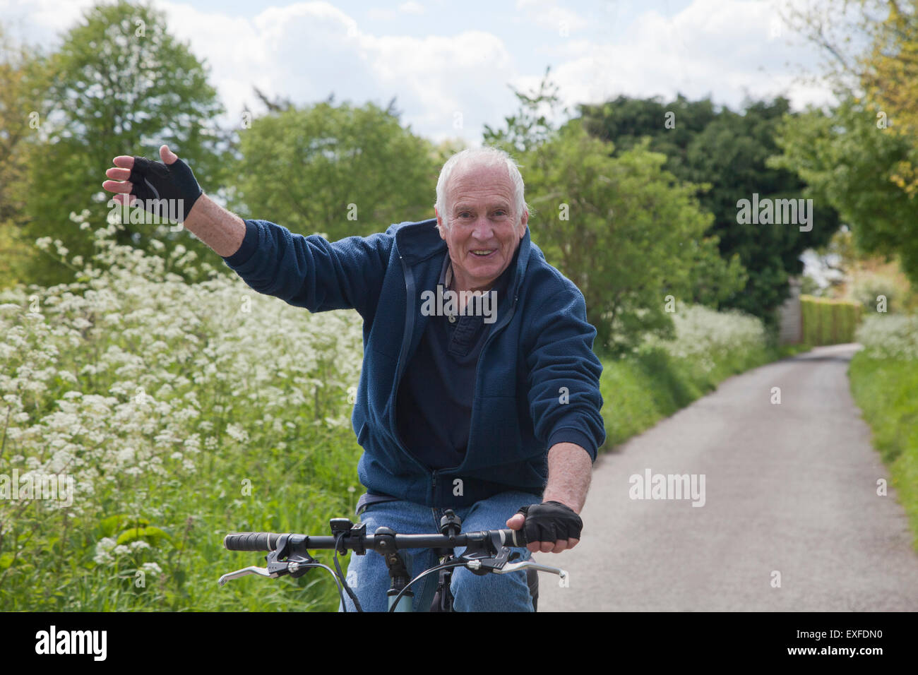 Senior man riding bike on country lane Banque D'Images
