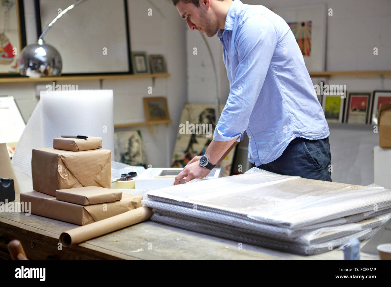 Man wrapping des cadres dans l'enveloppe de bulle sur table dans les encadreurs atelier Banque D'Images