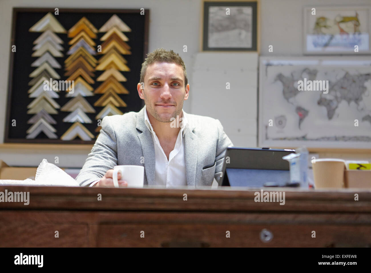 Portrait of mid adult man at desk dans les encadreurs atelier Banque D'Images