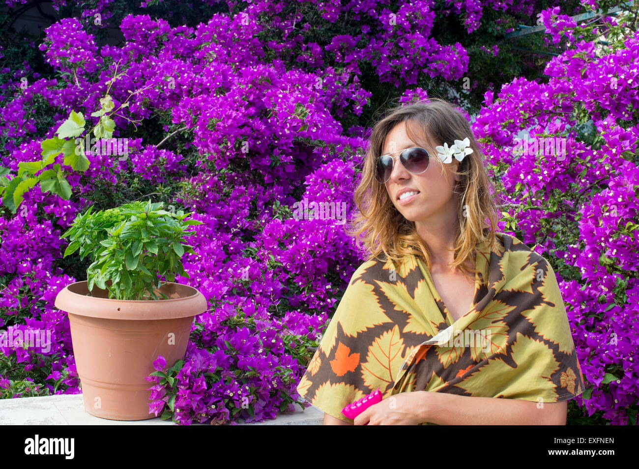 Jeune fille avec des lunettes et une fleur dans ses cheveux entouré par de belles fleurs violettes Banque D'Images