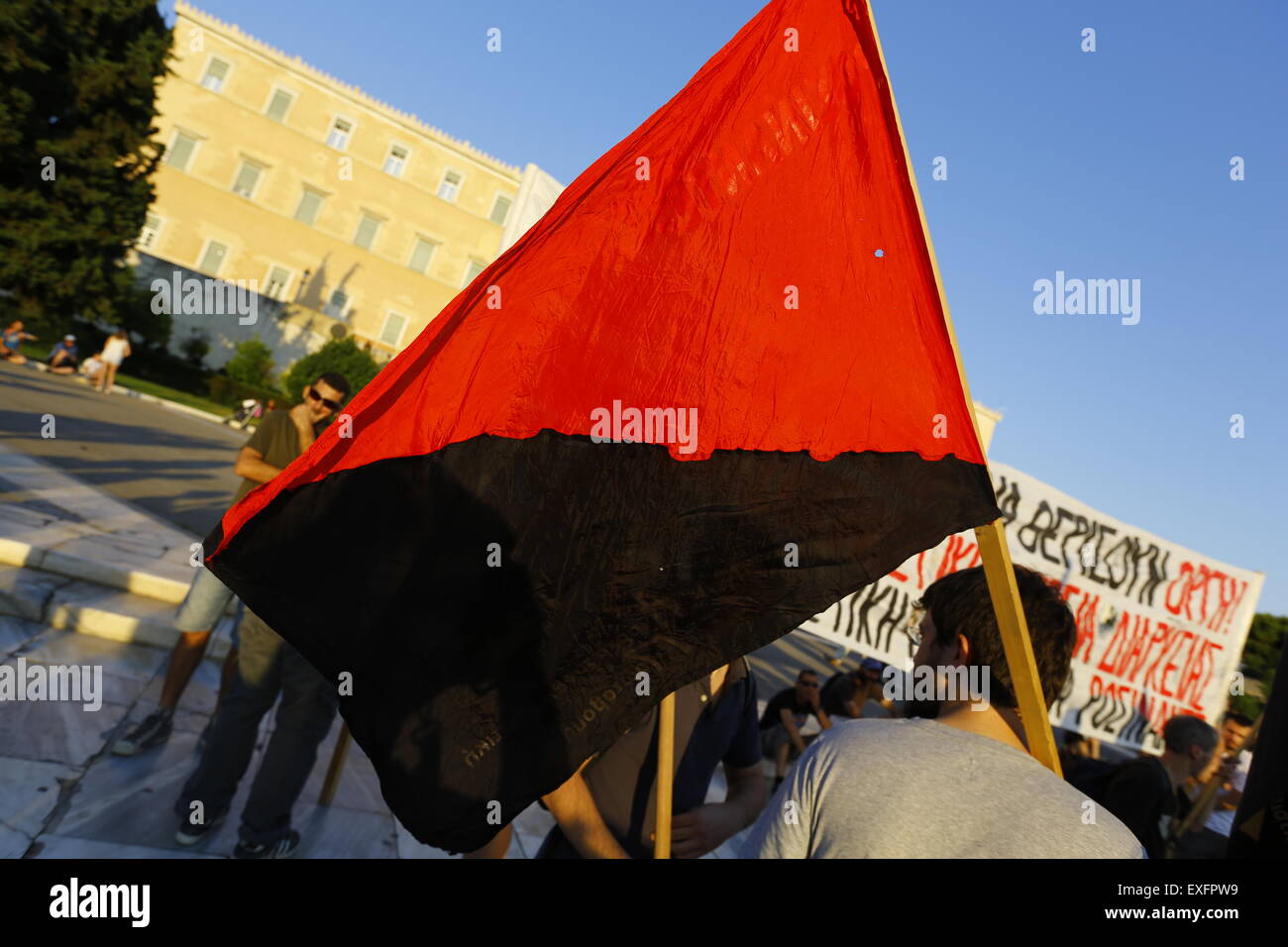 Athènes, Grèce. Le 13 juillet, 2015. Un manifestant tient un drapeau anarchiste rouge et noir anti-austérité à la manifestation devant le parlement grec. Les Grecs se réunissent près du Parlement grec sous la bannière de "nous laisser cette Europe". Ils ont appelé le gouvernement à ne pas céder à la demande des créanciers de la Grèce pour plus d'austérité, mais plutôt de quitter la zone euro. © Michael Debets/Pacific Press/Alamy Live News Banque D'Images