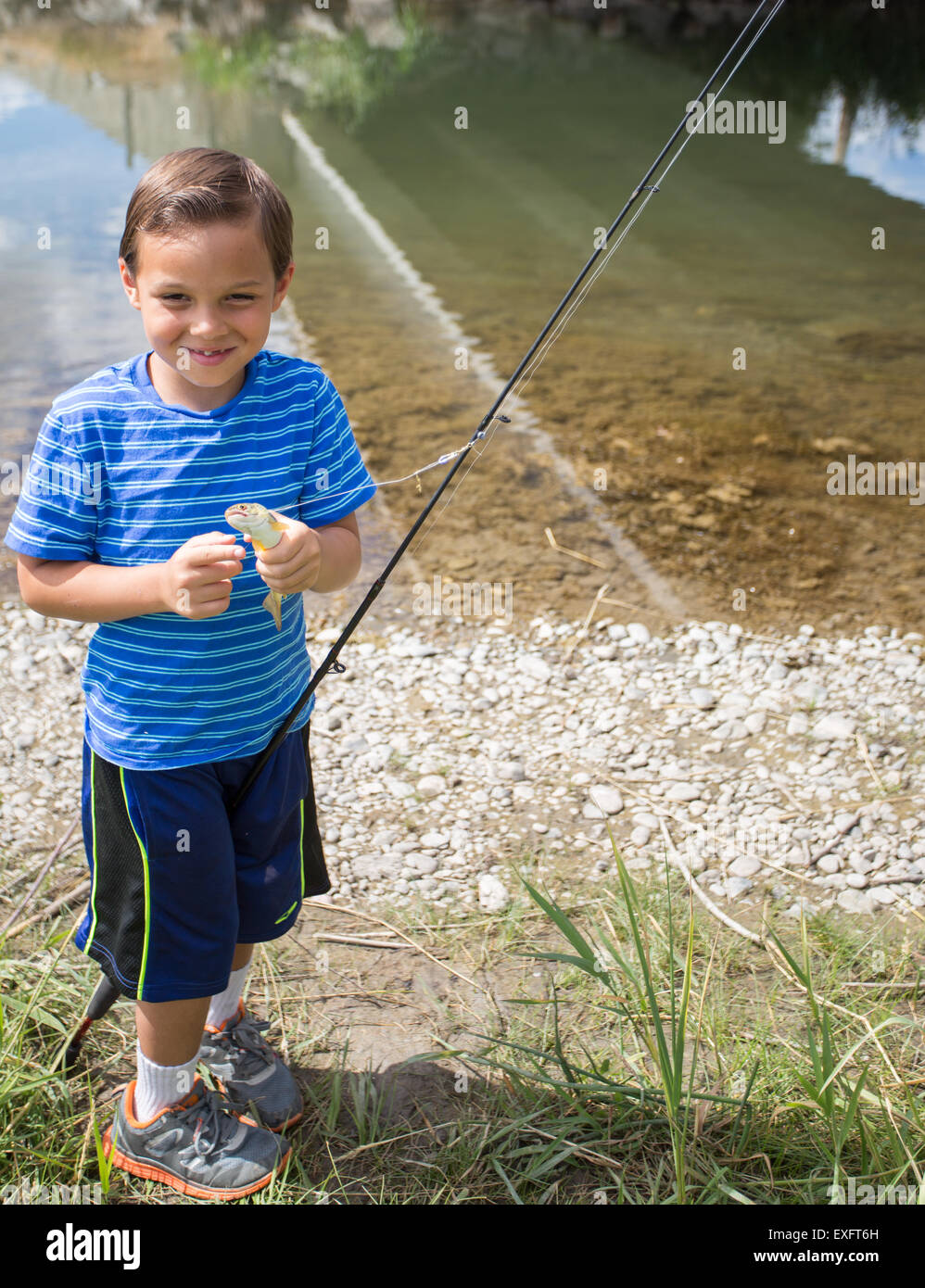 Jeune garçon montrant le poisson qu'il a pris. Banque D'Images