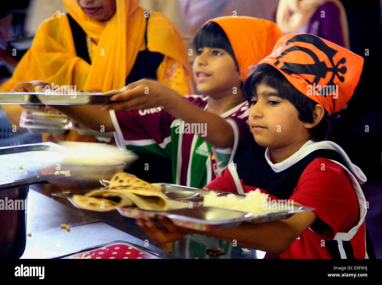 Les garçons sikhs recevoir langar le repas végétarien servi après le service dans un gurdwara Banque D'Images