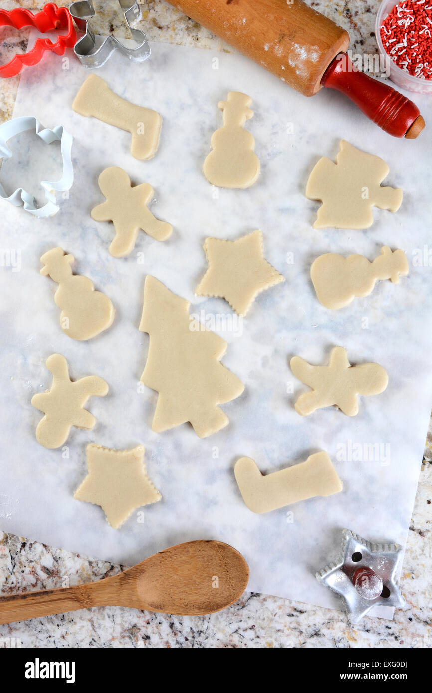 Formes de Biscuit de Noël sur le papier parchemin. Autour du périmètre sont coupeurs, remous de Sprinkles, cuillère et rouleau à pâtisserie. La verticale Banque D'Images