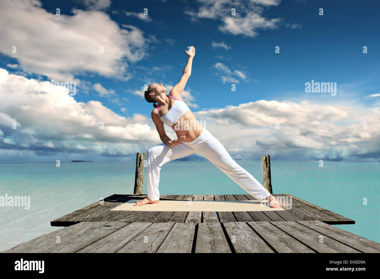 Jeune femme faisant de l'exercice de yoga à une mer Banque D'Images
